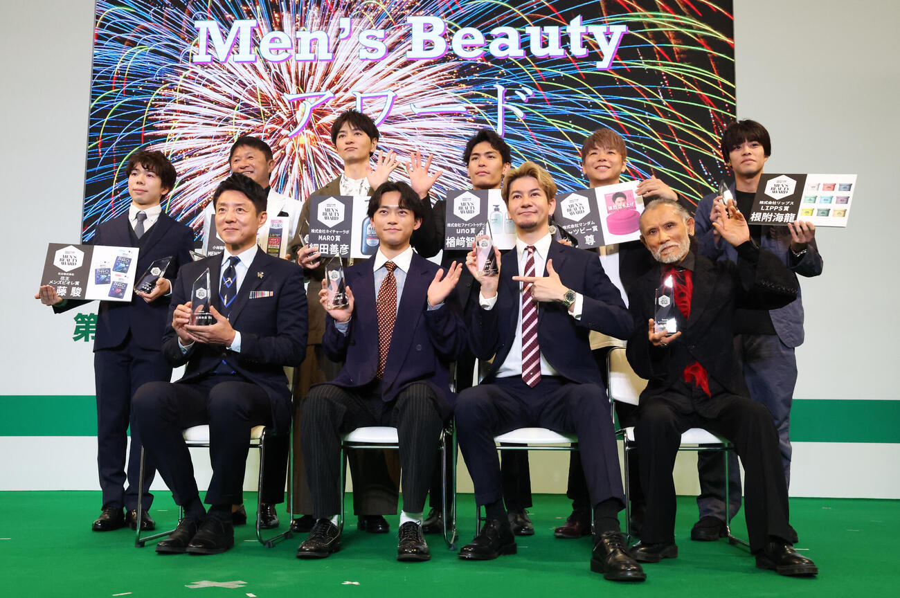 第6回Men's BeautyアワードでTVカメラに向かって手を振る受賞者の、前列左から松岡修造、中山翔貴、JOY、片岡鶴太郎。後列左から佐藤駿、武田修宏、細田義彦、楢崎智亜、武尊、根附海龍（撮影・丹羽敏通）