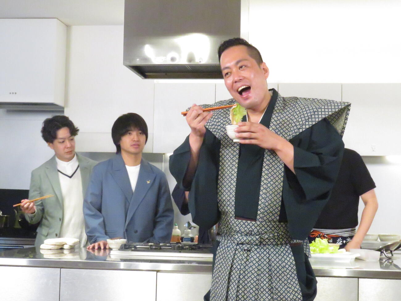 「たくろう万博」で提供する「しゃ奉行町田監修！　こだわりのポン酢で食べるしゃぶしゃぶ」を実際に作り、奉行のような格好でポーズを取るエバースの町田和樹（手前）。後方左から2人目の相方、佐々木隆史は、その様子に冷ややかな視線を送っていた