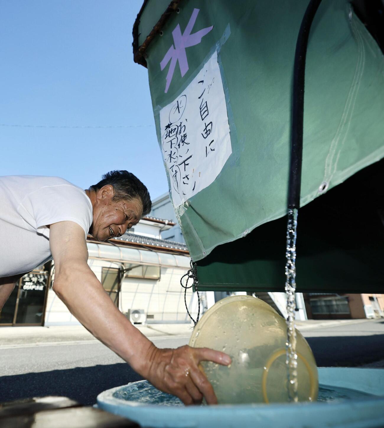 熊本県八代市鏡町の高田鮮魚店で地下水をくむ男性。店を夫と営む高田景子さんは「水は生活に必須。店は営業できないが、地域に少しでも元気を与えられれば」と、無料で提供することを決めた。多くの人が訪れ、容器に入れた水を持ち帰っていた＝1日午前8時59分（共同）