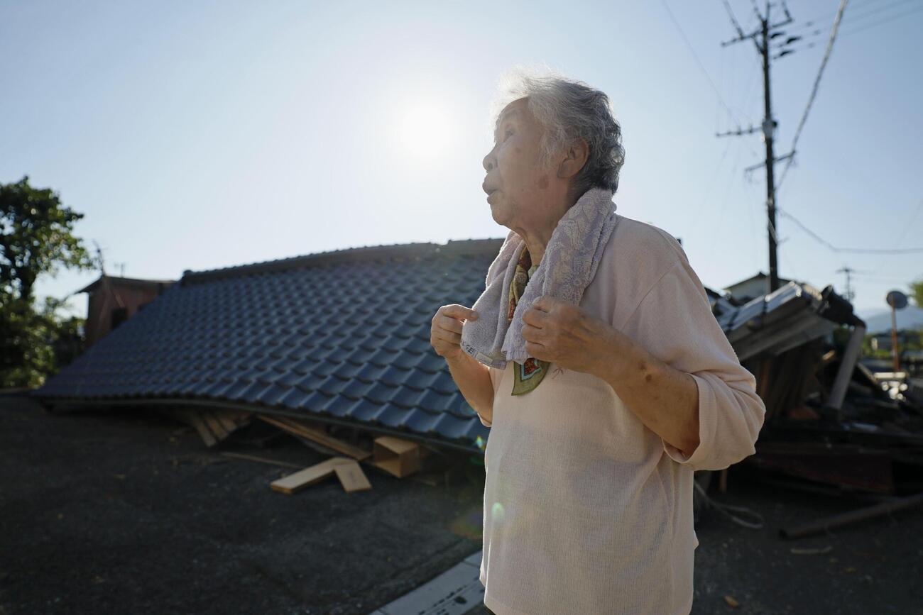 倒壊した自宅の前で話す寺田美代子さん（88）。被災時、自宅内で身動きがとれず、近所の人に助け出された。その後まもなくで屋根が落ちた。「10年前の地震とは全く違う。バリバリと揺れ、家のものが全て落ちてきた」と振り返った＝1日午前7時32分、熊本県八代市（共同）