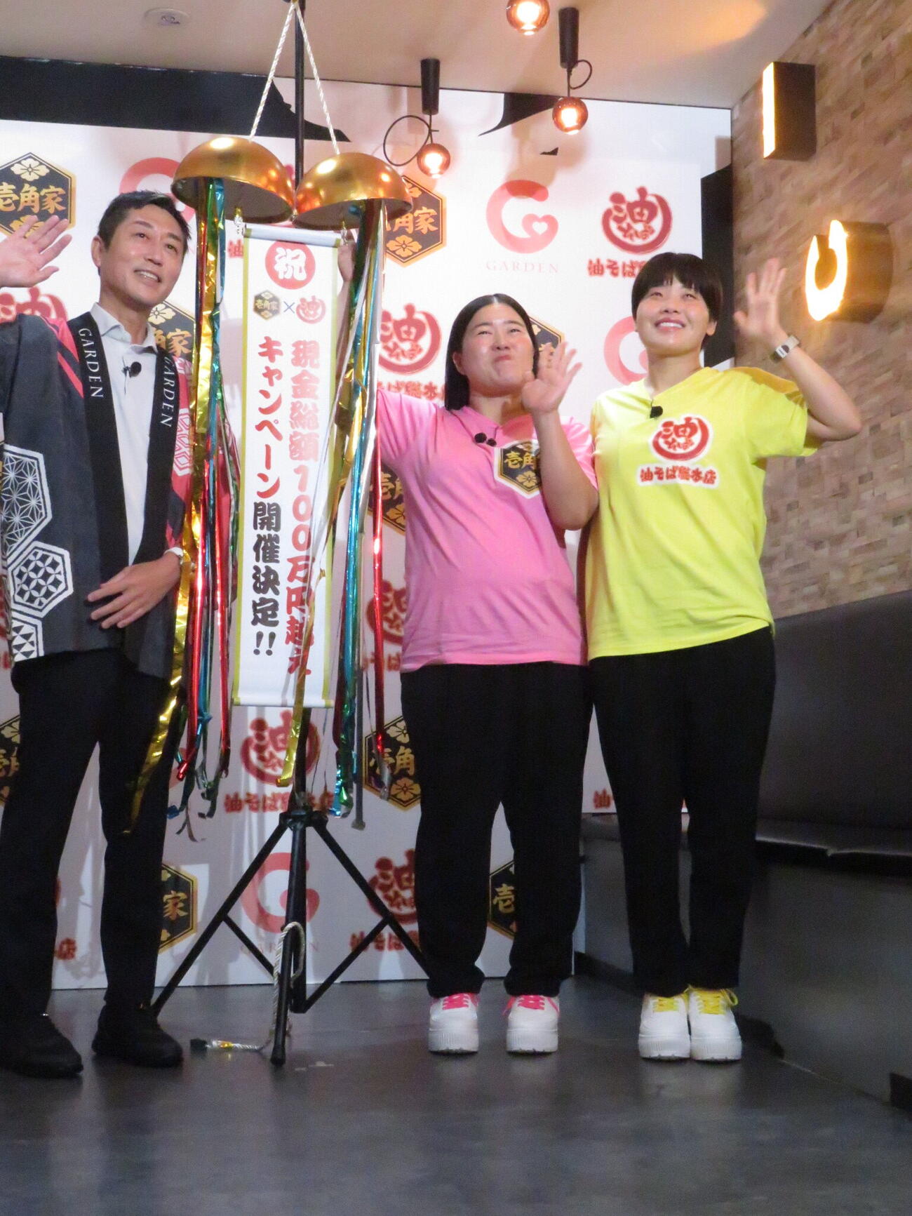 「壱角家×油そば総本店『爆速！！　100日100店舗二刀流ハイブリッド導入達成記念キャンペーン』発表会」に参加したガンバレルーヤのよしこ（中央）とまひる（右）。左は株式会社ガーデンの川島賢社長