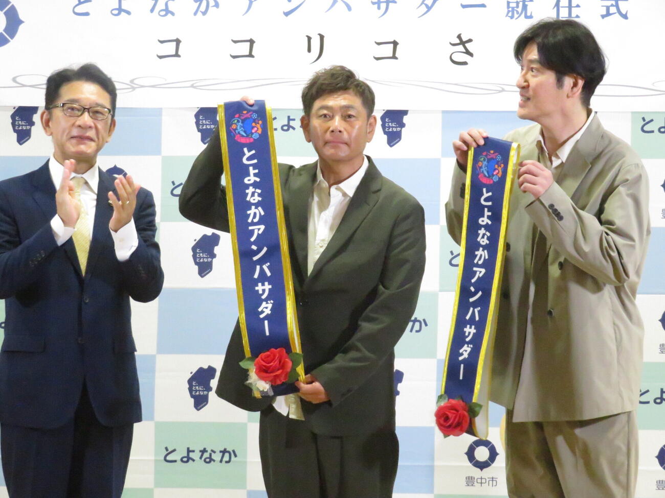 「とよなかアンバサダー」に就任し、大阪・豊中市の長内繁樹市長（左）からたすきを受け取ったココリコの遠藤章造（中央）と田中直樹