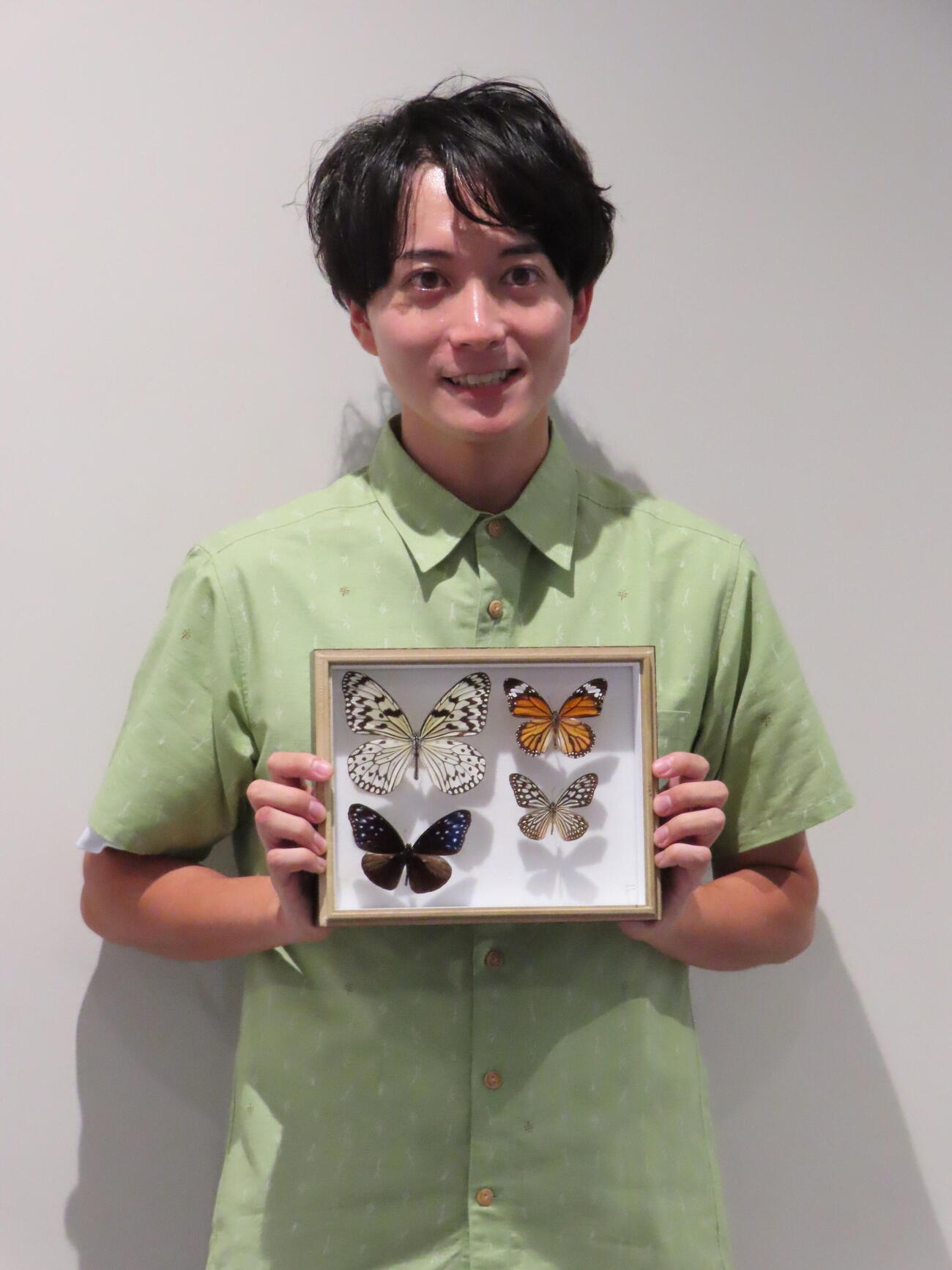 チョウの標本を手に笑顔の牧田習（撮影・鎌田良美）