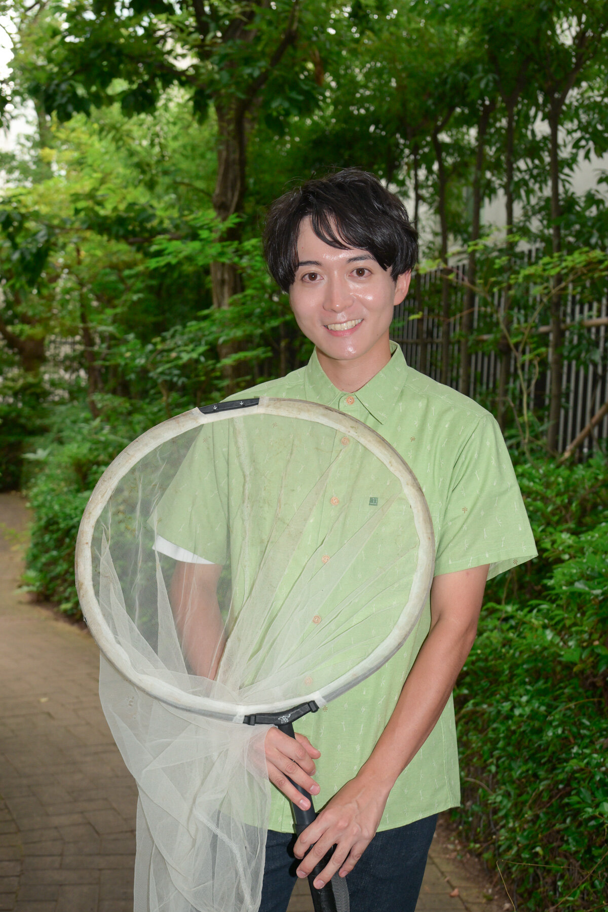 屋外で大きな虫捕り網を持つ牧田習