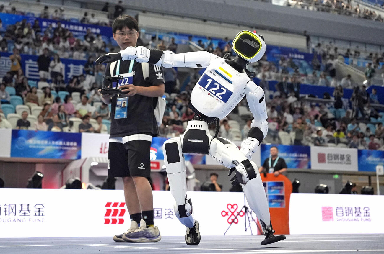 23日、北京での「世界人型ロボットスポーツ大会」で400メートルのスタート前にバランスを崩すロボット（共同）