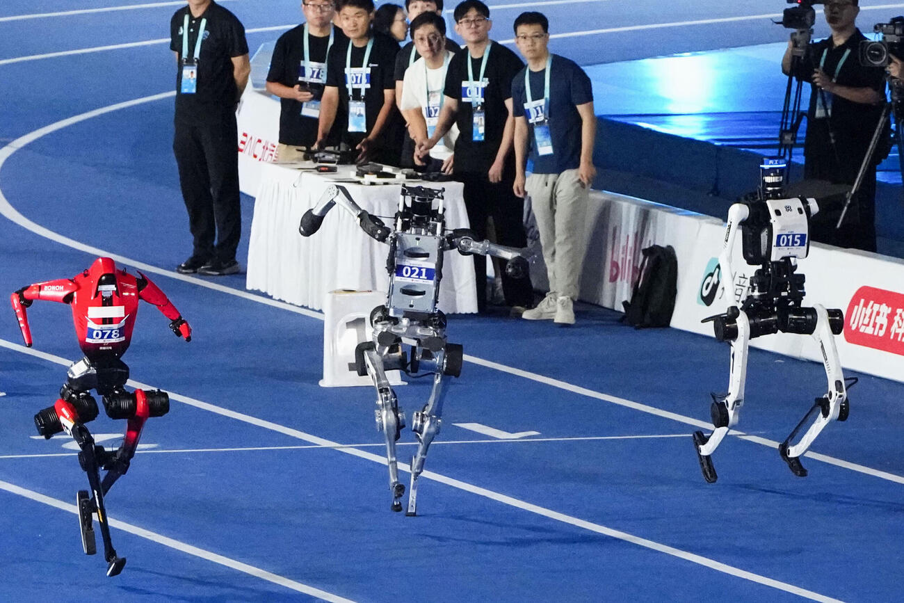 「世界人型ロボットスポーツ大会」の陸上100メートル予選で9秒39のタイムをたたき出した北京人形機器人創新中心が手がけた「天工」（右）＝22日、北京（共同）