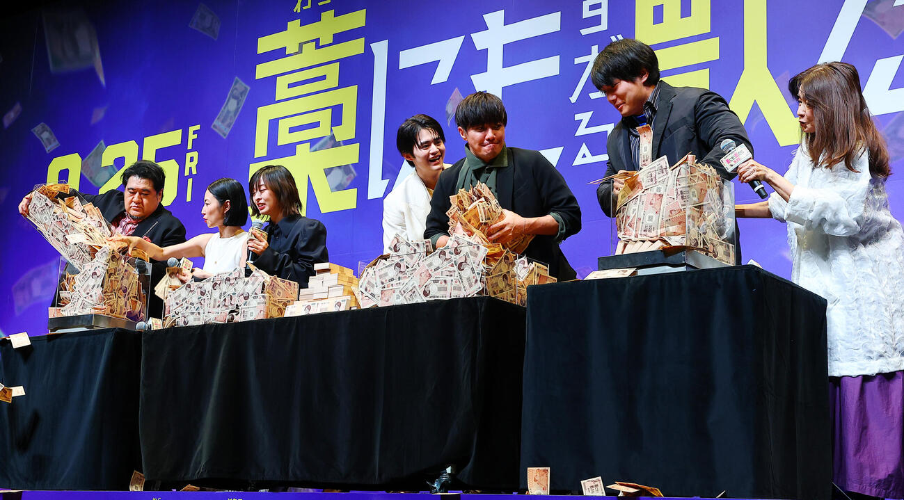 映画「藁にもすがる獣たち」完成披露舞台あいさつに登場し、1億円重量当てゲームを行う、左から小手伸也、MEGUMI、森七菜、鈴鹿央士、成宮寛貴、青木マッチョ、風吹ジュン（撮影・野上伸悟）