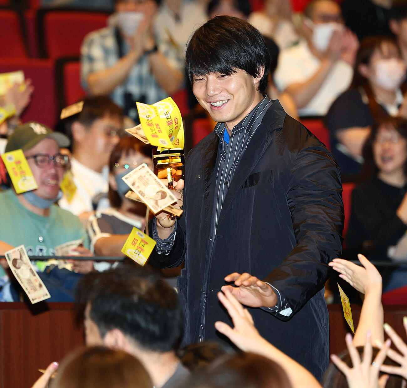 映画「藁にもすがる獣たち」完成披露舞台あいさつに登場し、マネーガンで疑似紙幣を飛ばす青木マッチョ（撮影・野上伸悟）