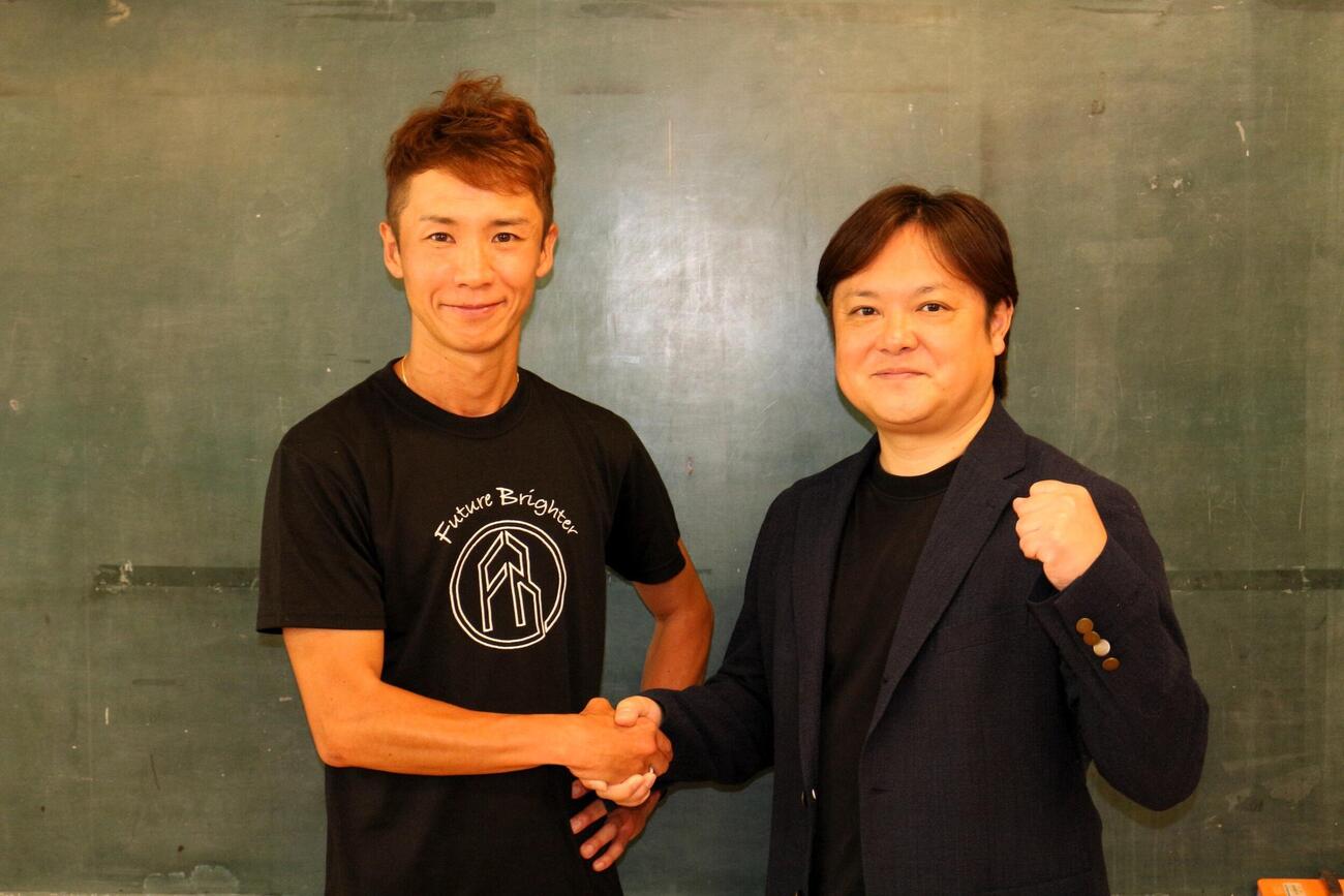 ランニング芸人の宇野けんたろう（左）は、スポンサー契約を結んだFBモーゲージの根石高宏社長と握手を交わした