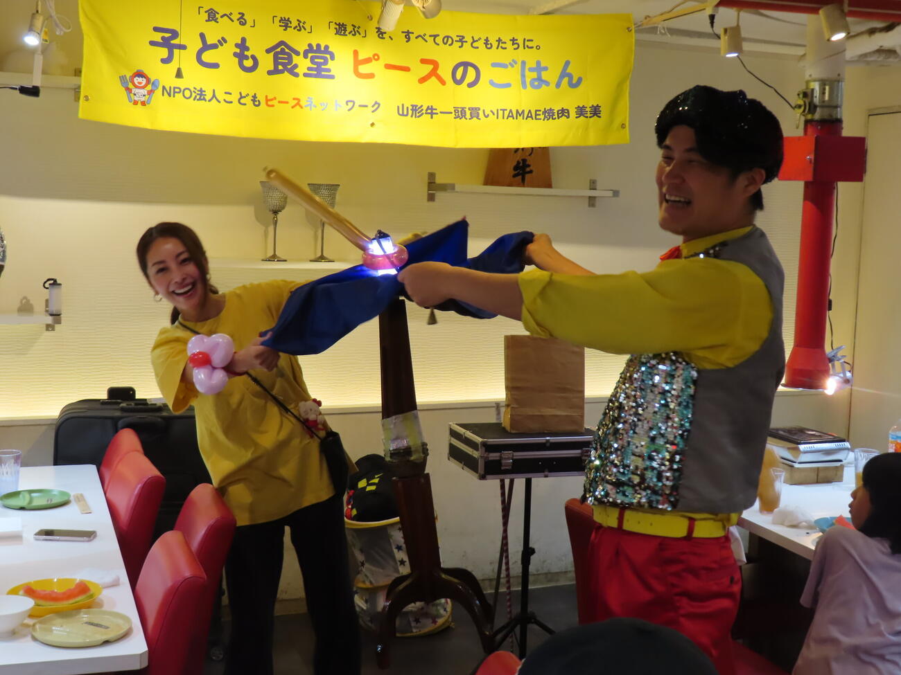 子ども食堂「ピースのごはん」で熊切あさ美（左）はハッピーつついとパフォーマンスを披露する