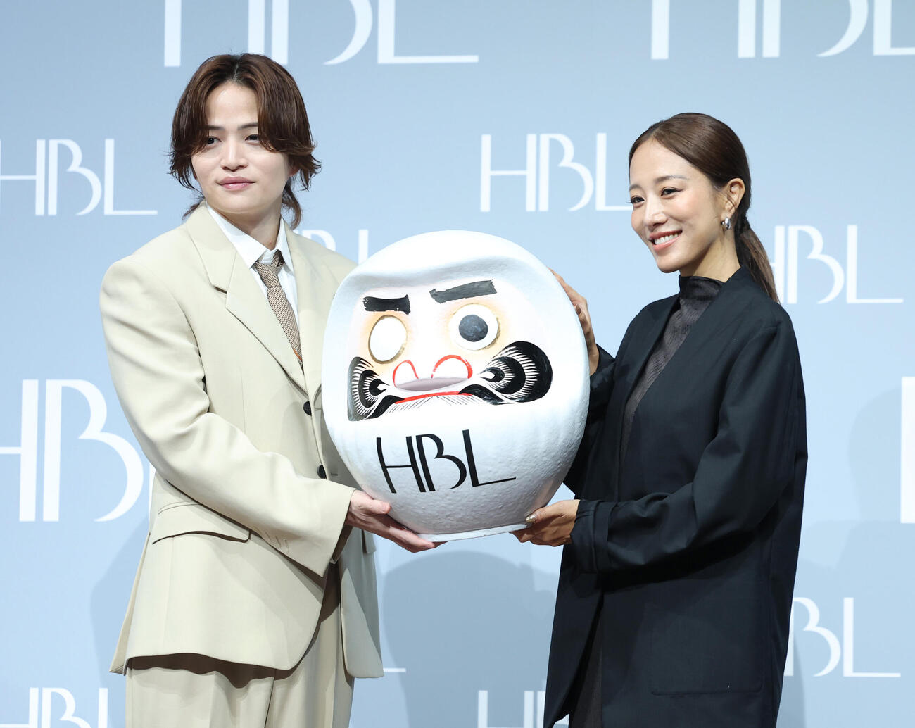 新CM発表会に登壇し株式会社JULIA IVY福井仁美代表取締役社長（左）にだるまを贈呈する菊池風磨（撮影・増田悦実）