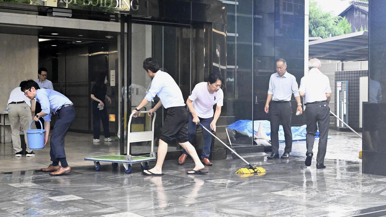 大雨で浸水したビルの出入り口を清掃する従業員ら（共同）