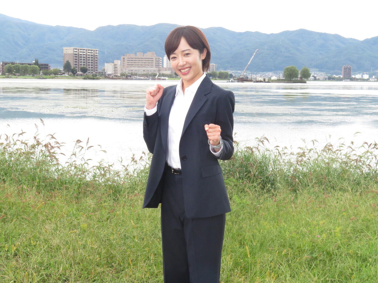 クランクインした「巡るスワン」のロケ地、長野・諏訪市の諏訪湖をバックにスーツ姿で笑顔を見せる森田望智