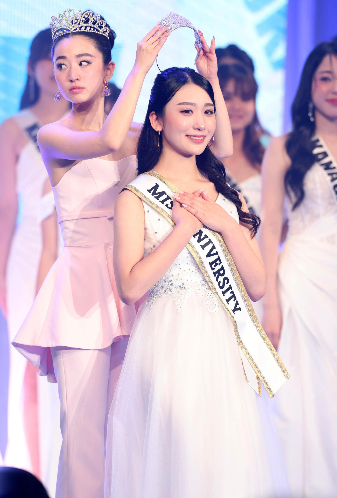 ミスユニバーシティ2026でグランプリに輝いた東京代表の熊丸うた子さん（手前）は飯田樺楽さんからティアラをかぶせてもらう（撮影・浅見桂子）