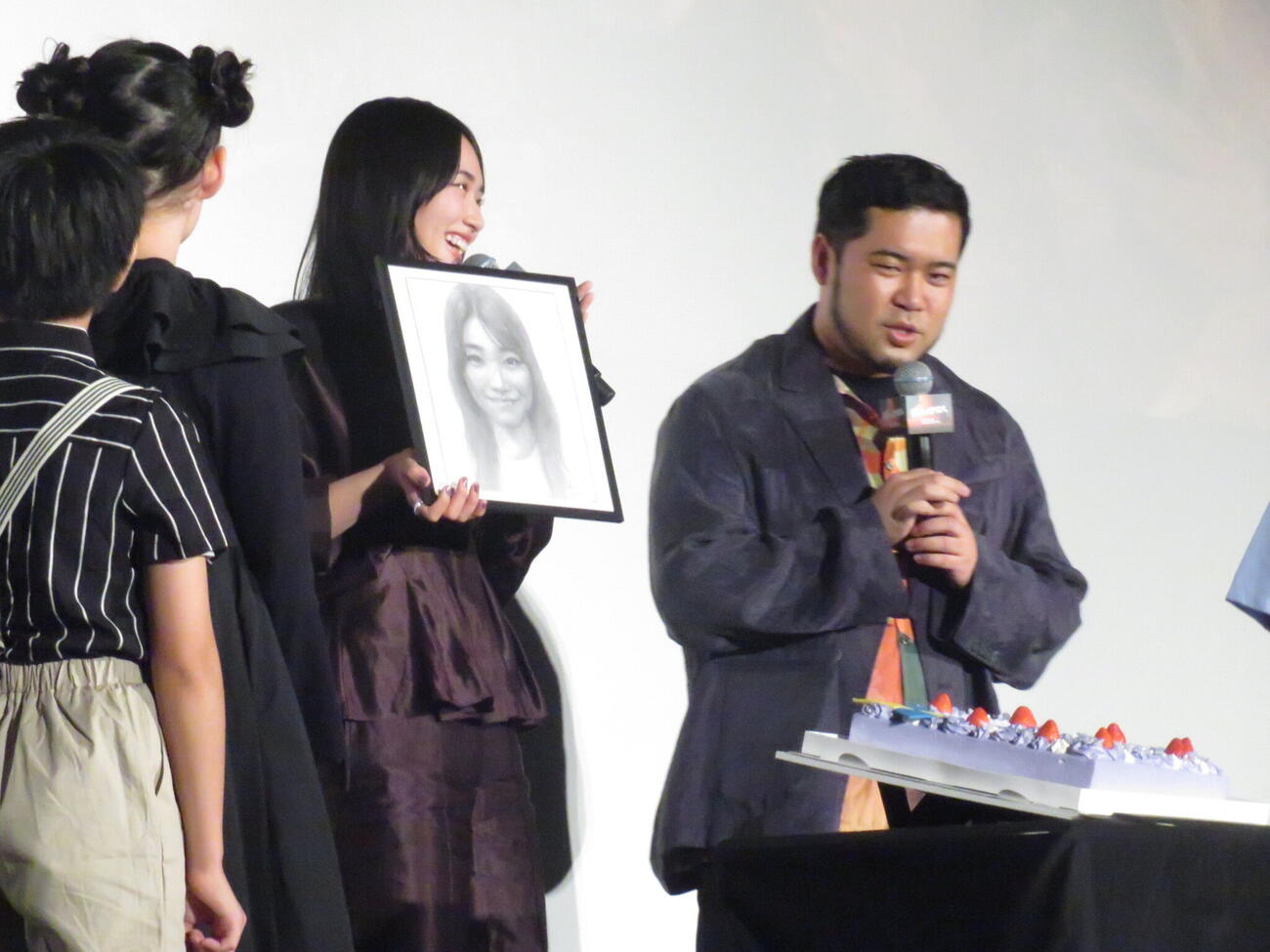 映画「我々は宇宙人」の初日舞台あいさつで、3日後に迫った誕生日を一足早く祝福され、誕生日ケーキと似顔絵をプレゼントされた櫻坂46の山﨑天（中央）。右は令和ロマンの松井ケムリ