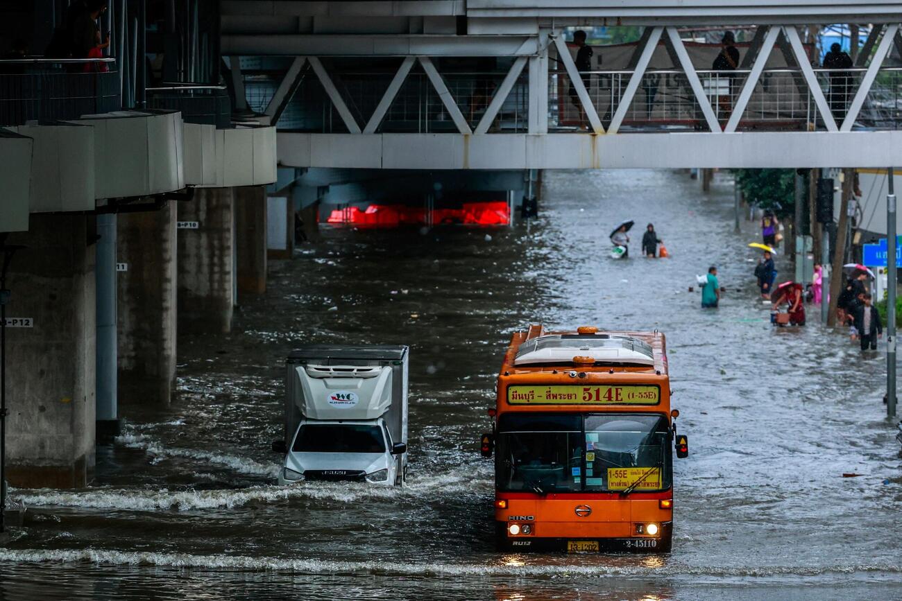 タイ・バンコクで大雨により冠水した道路を進む車両(ロイター)