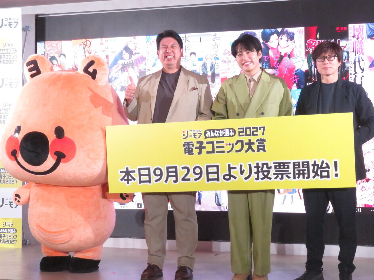 「コミックシーモア『みんなが選ぶ！！電子コミック大賞2027』投票開始発表会」に出席した、左からコミックシーモア公式キャラクターのヨムビー、「レインボー」ジャンボたかお、池田直人、NTTソルマーレの石井隆祐取締役