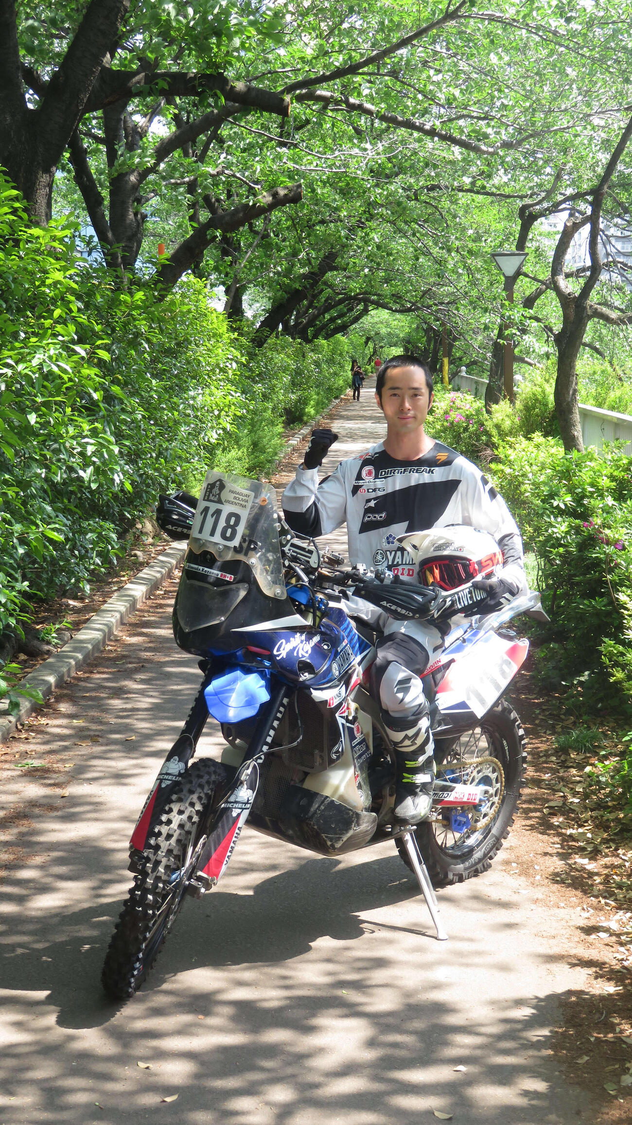 17年ダカール・ラリーで実際に使った愛車のバイクに乗りガッツポーズする風間晋之介（19年5月撮影）