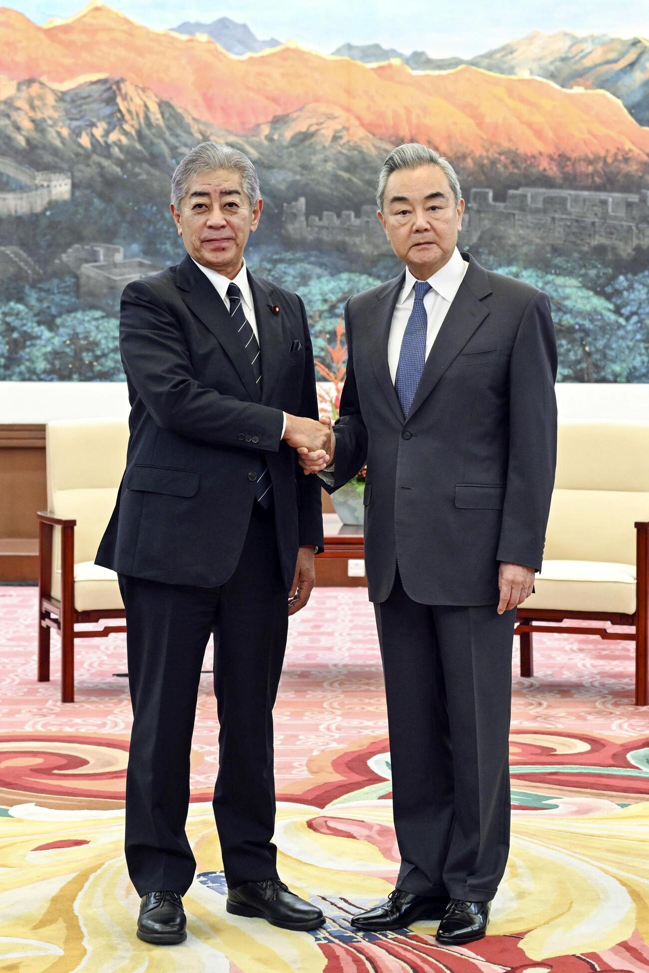 28日、中国の王毅外相（右）と握手する岩屋毅前外相（新華社＝共同）