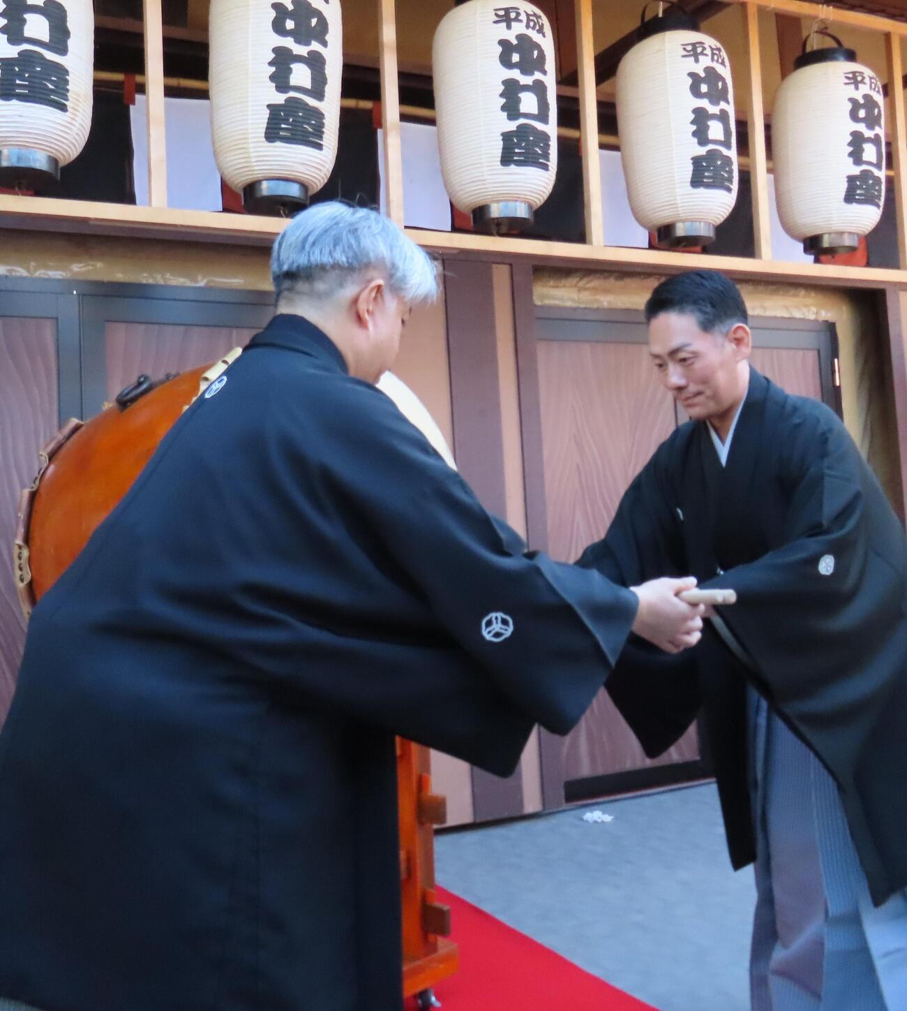 「平成中村座　十月大歌舞伎」初日の「一番太鼓の儀」でばちを手渡す中村勘九郎（右）