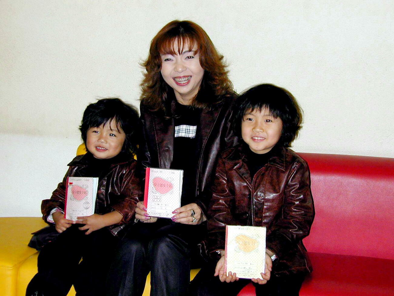 2002年3月、第3子妊娠を発表。母子手帳を手に笑顔を見せるハイヒールモモコ（中央）。右は長男仁一郎くん、左は二男政之助くん