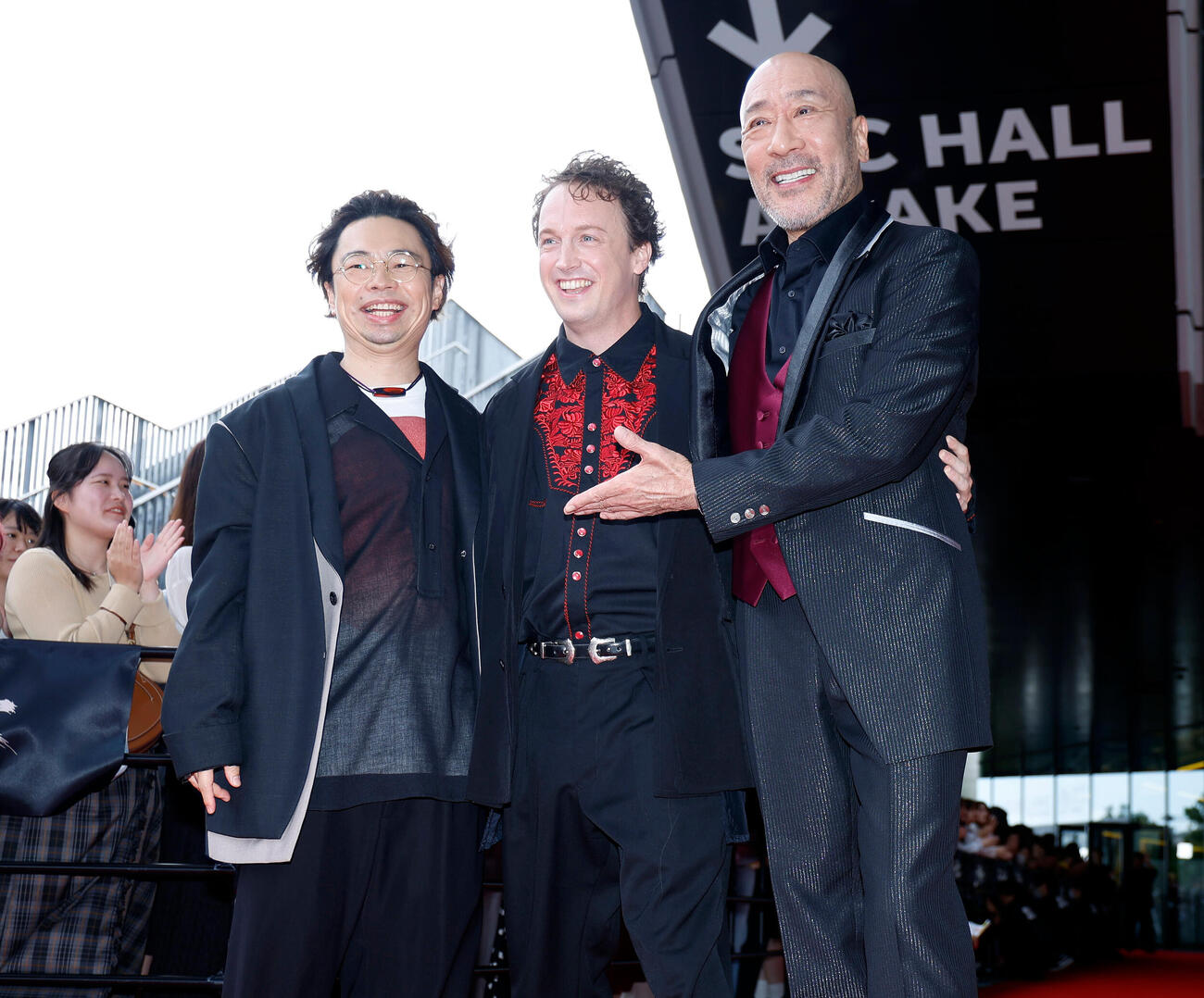 レッドカーペットを歩き、記念撮影を行う登壇者、左から浜野謙太、ジョエル・ディカーソン、牧野公昭（撮影・山本朝陽）