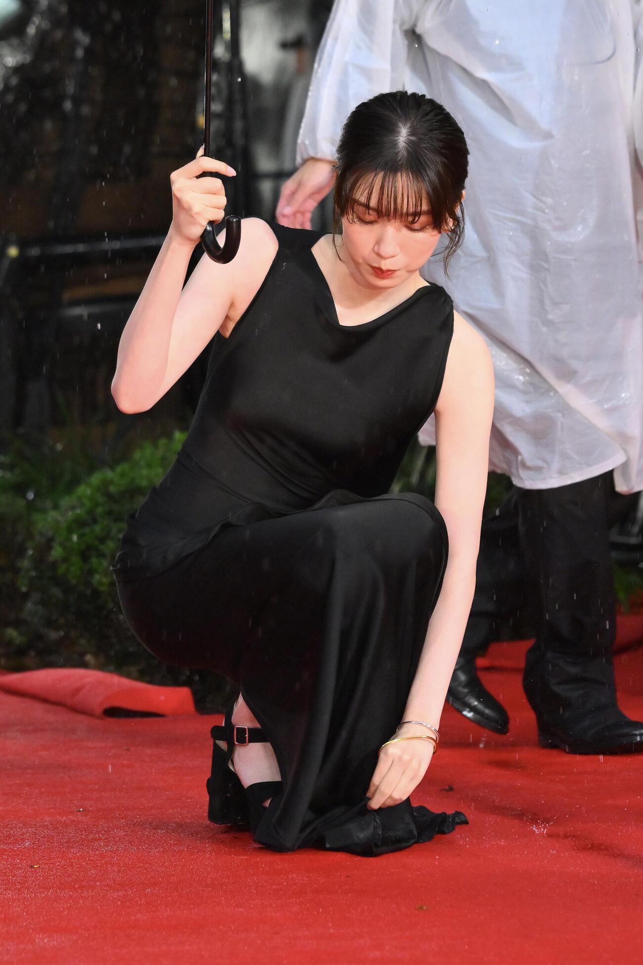 オープニングイベントレッドカーペットで濡れたドレスを手に取る永野芽郁（撮影・滝沢徹郎）