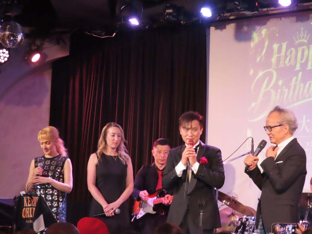 2026年10月25日、ケニー大倉（左から3人目）の祝福に駆けつけたMax Luxのアリシア、ラーナ、1人おいて作詞家売野雅勇氏