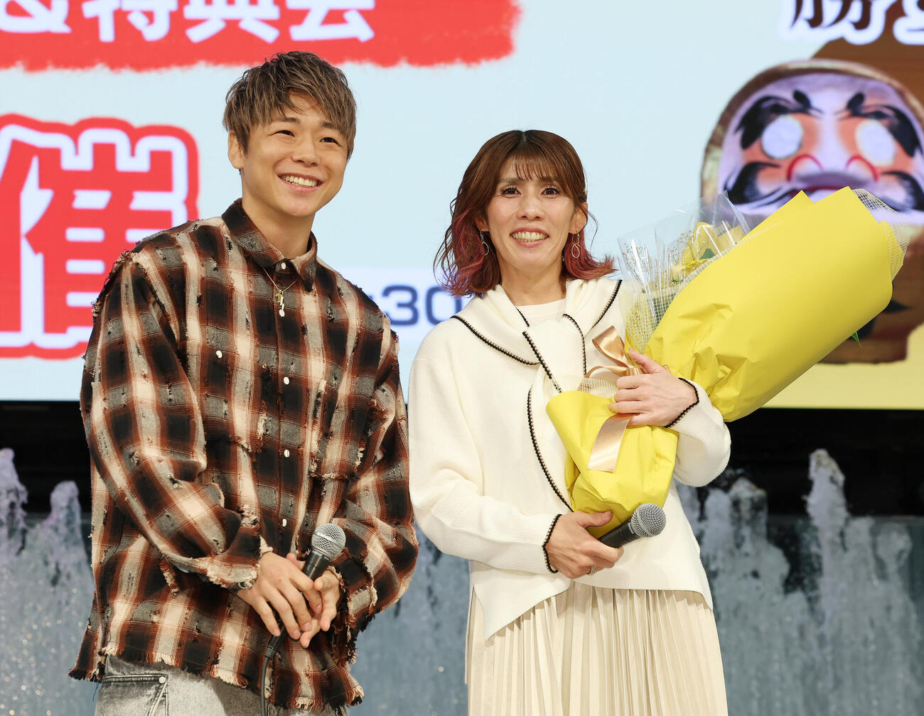 デビューシングル発売記念イベントにサプライズで登場した武尊（左）から花束を受け取った吉田沙保里（撮影・宮地輝）