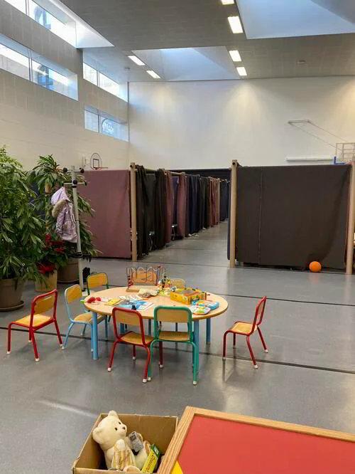 避難者向けに開放されたパリ10区の体育館。子ども用の遊具が並ぶスペースの向こうに「個室エリア」が設けられている（写真：筆者撮影）