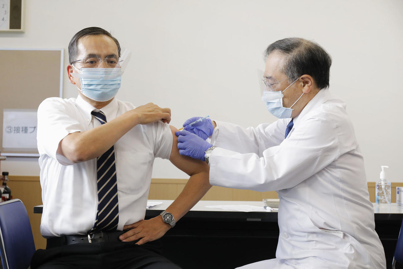 新型コロナウイルス感染症の第1例目のワクチン接種を受ける国立病院機構東京医療センターの新木一弘院長（左）（共同）