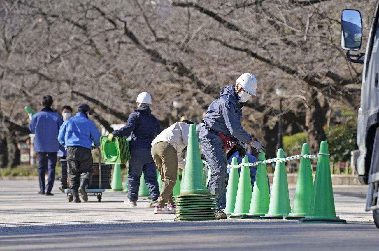 新型コロナウイルス感染拡大防止のため、東京・上野公園の大通りにパイロンを設置し片側通行にする作業員ら（共同）