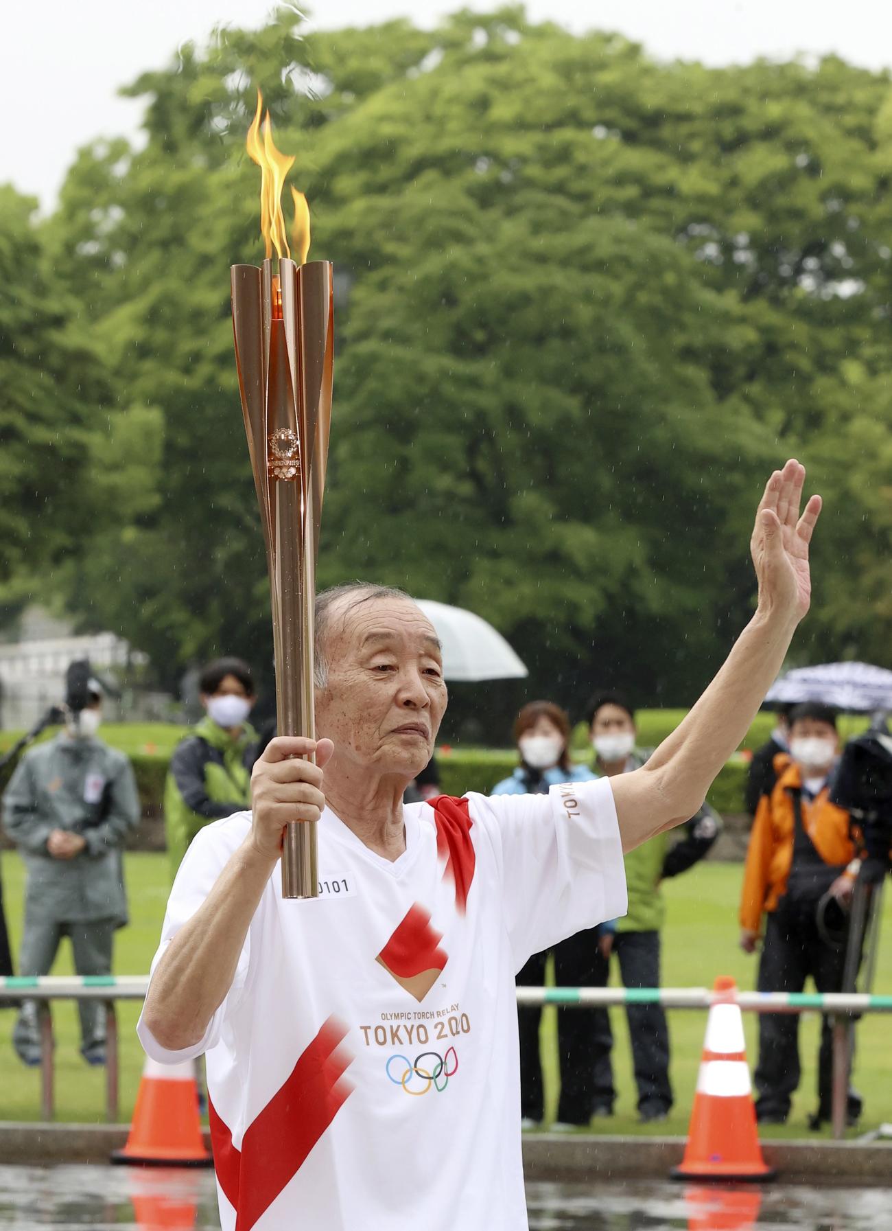 聖火の点火式で手を振る坂井孝之さん（共同）