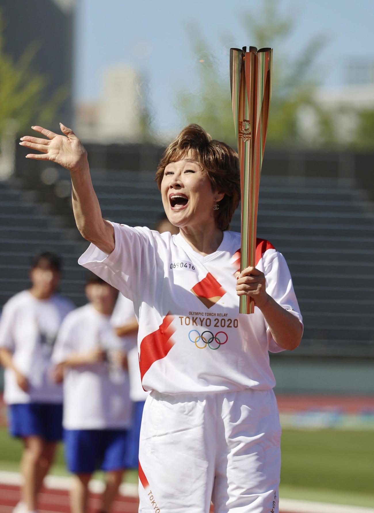 集まった人たちに笑顔で手を振る聖火ランナーを務めた小林幸子（共同）
