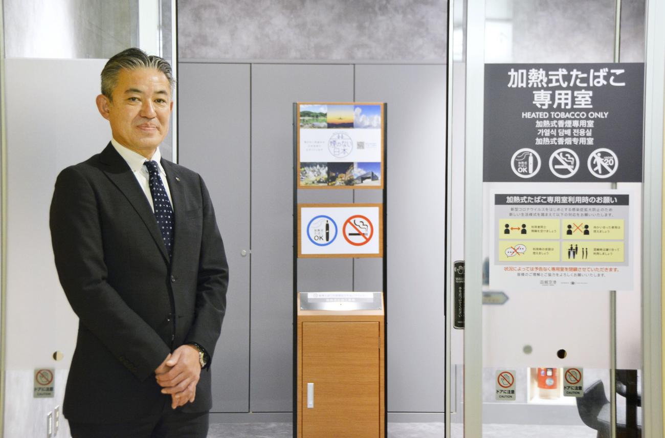 函館空港ビル内にある加熱式たばこ専用の喫煙所の前に立つ八島聡社長（共同）