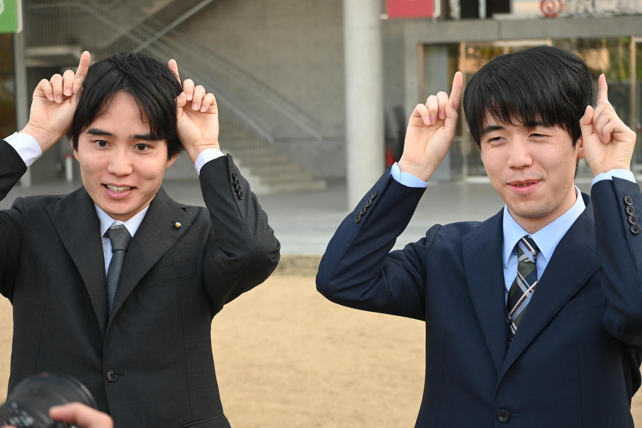 竜王戦7番勝負第4局の対局会場となる大阪府茨木市の複合施設「おにクル」に到着し、“鬼のポーズ”を決める佐々木勇気八段（左）藤井聡太竜王（撮影・松浦隆司）
