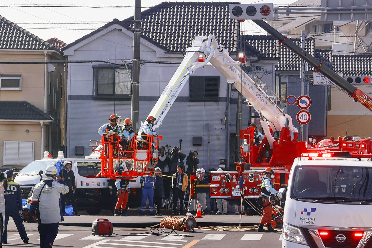 道路が陥没した県道交差点で対応に当たる当局者ら（共同）