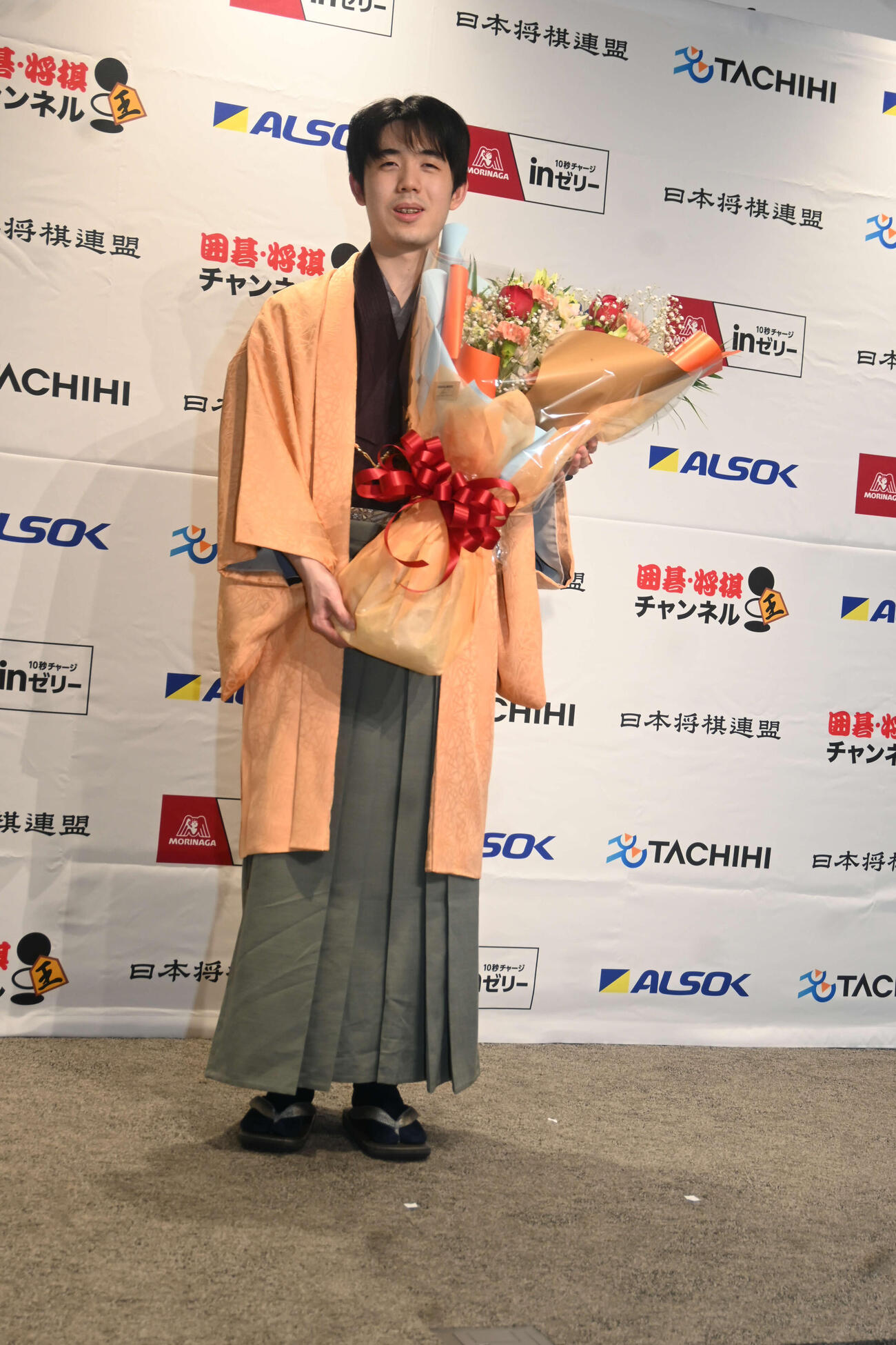 記者会見前に花束を贈られた藤井聡太王将（撮影・松浦隆司）