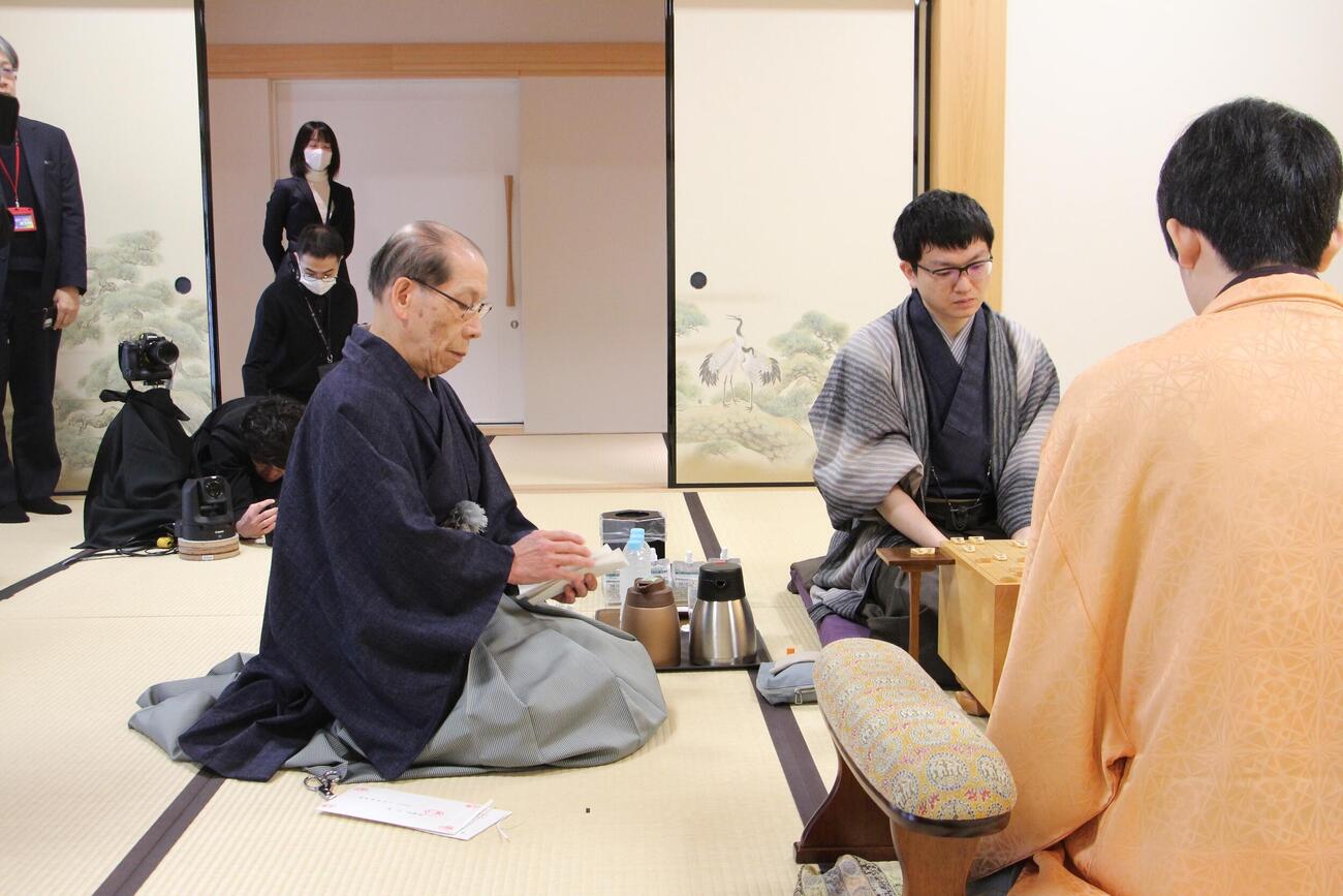 王将戦7番勝負第7局2日目、永瀬拓矢九段の封じ手を開封する立会人の桐山清澄九段（左）、手前は藤井聡太王将（日本将棋連盟提供）
