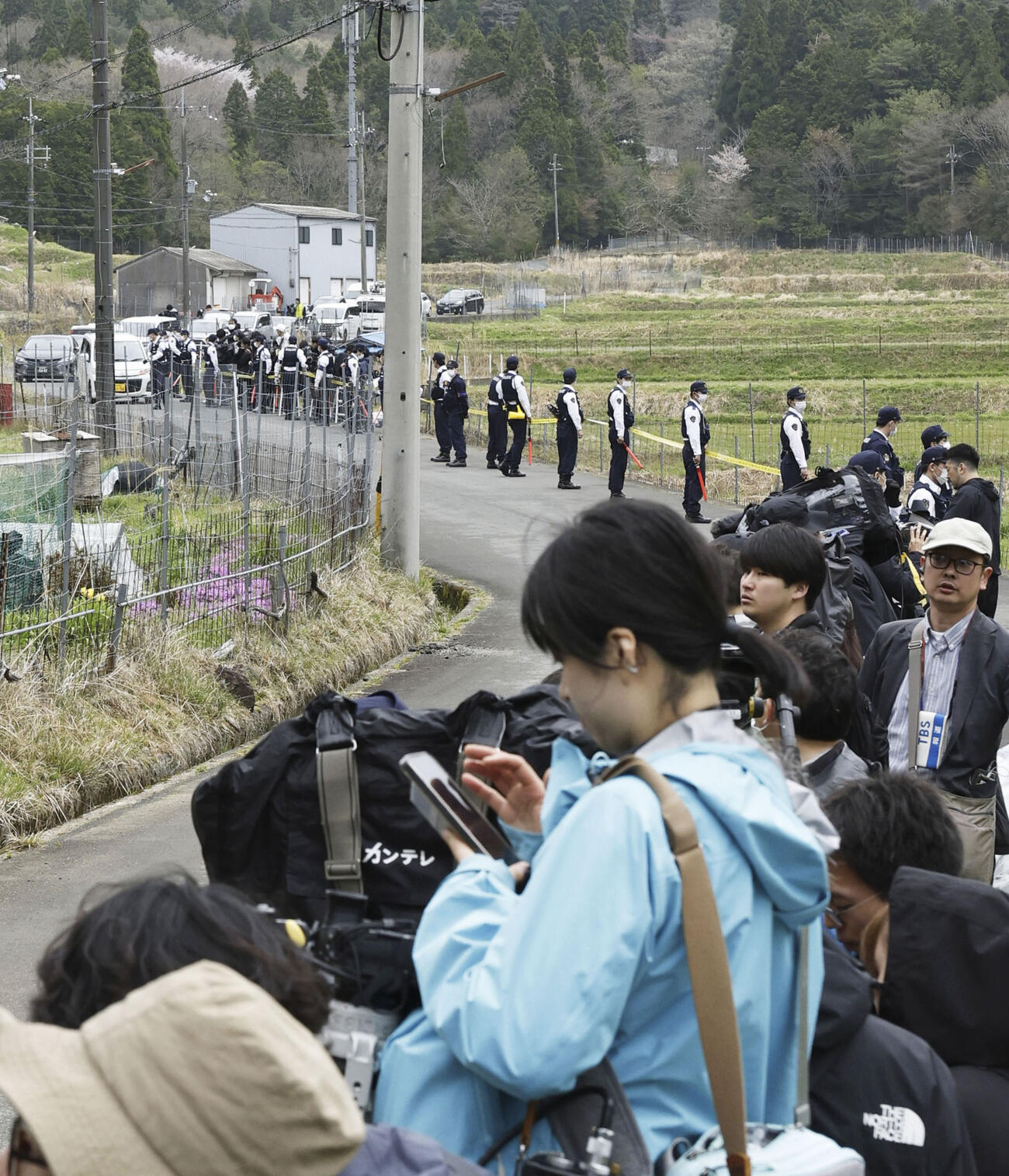 安達結希さんの自宅付近に集まった報道陣と、警戒にあたる警察官（共同）