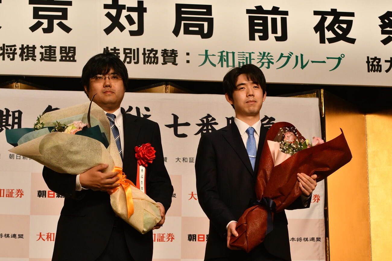 2026年4月7日、名人戦第1局前夜祭で贈呈された花束を手にする挑戦者の糸谷哲郎八段（左）と藤井聡太名人