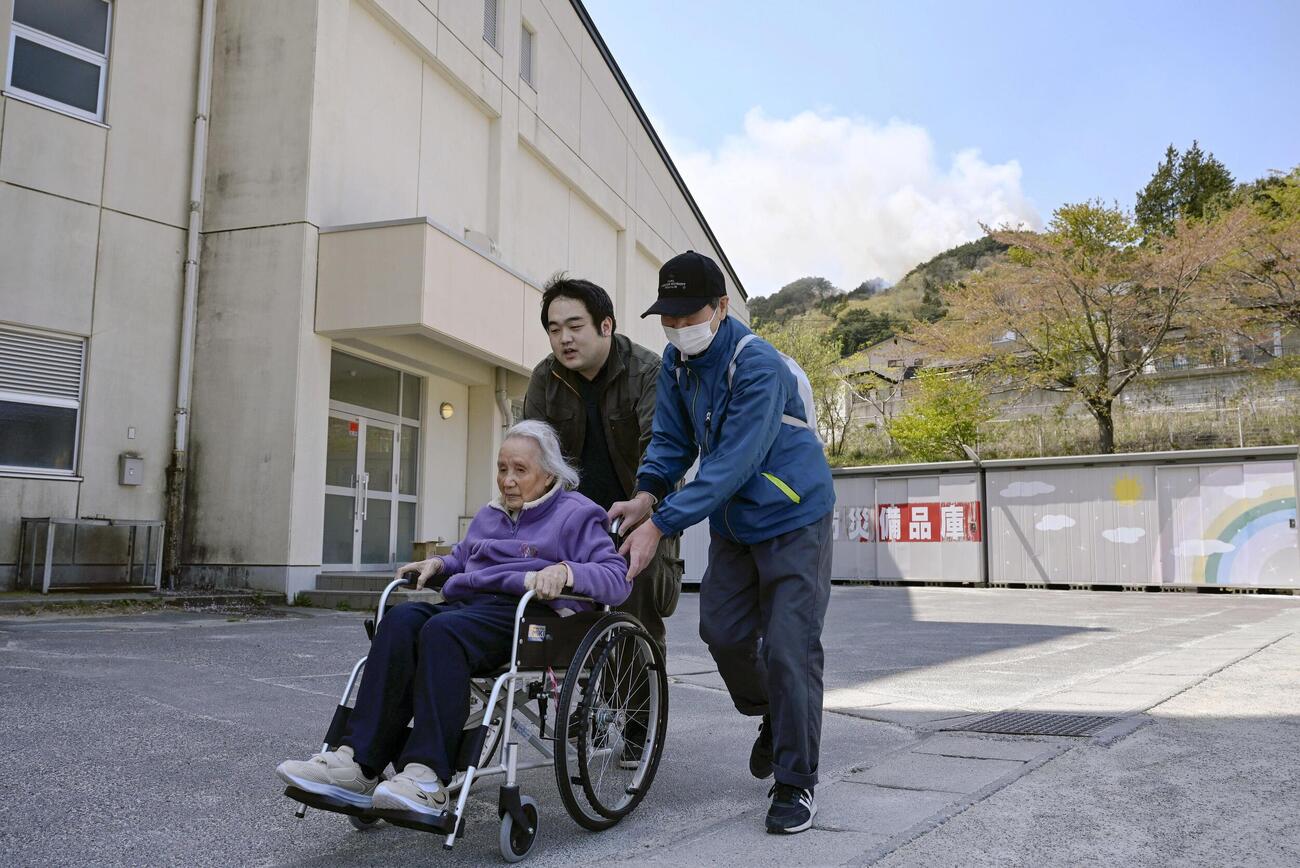 避難所の吉里吉里学園小学部の近くでも火災が起こり、再避難する人たち＝24日午後、岩手県大槌町(共同)