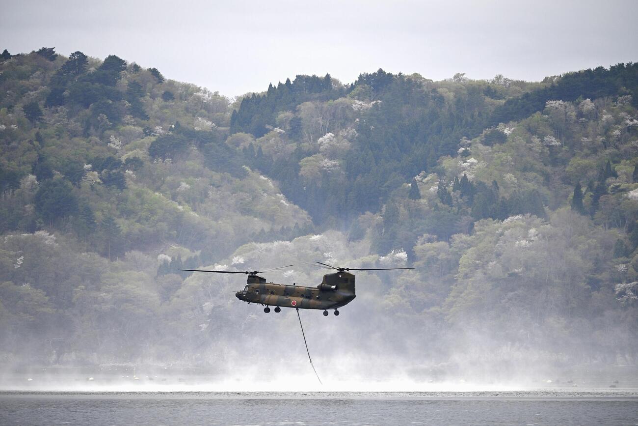 山林火災の消火活動のため、海水をくみ上げるヘリコプター＝27日午前、岩手県大槌町(共同)