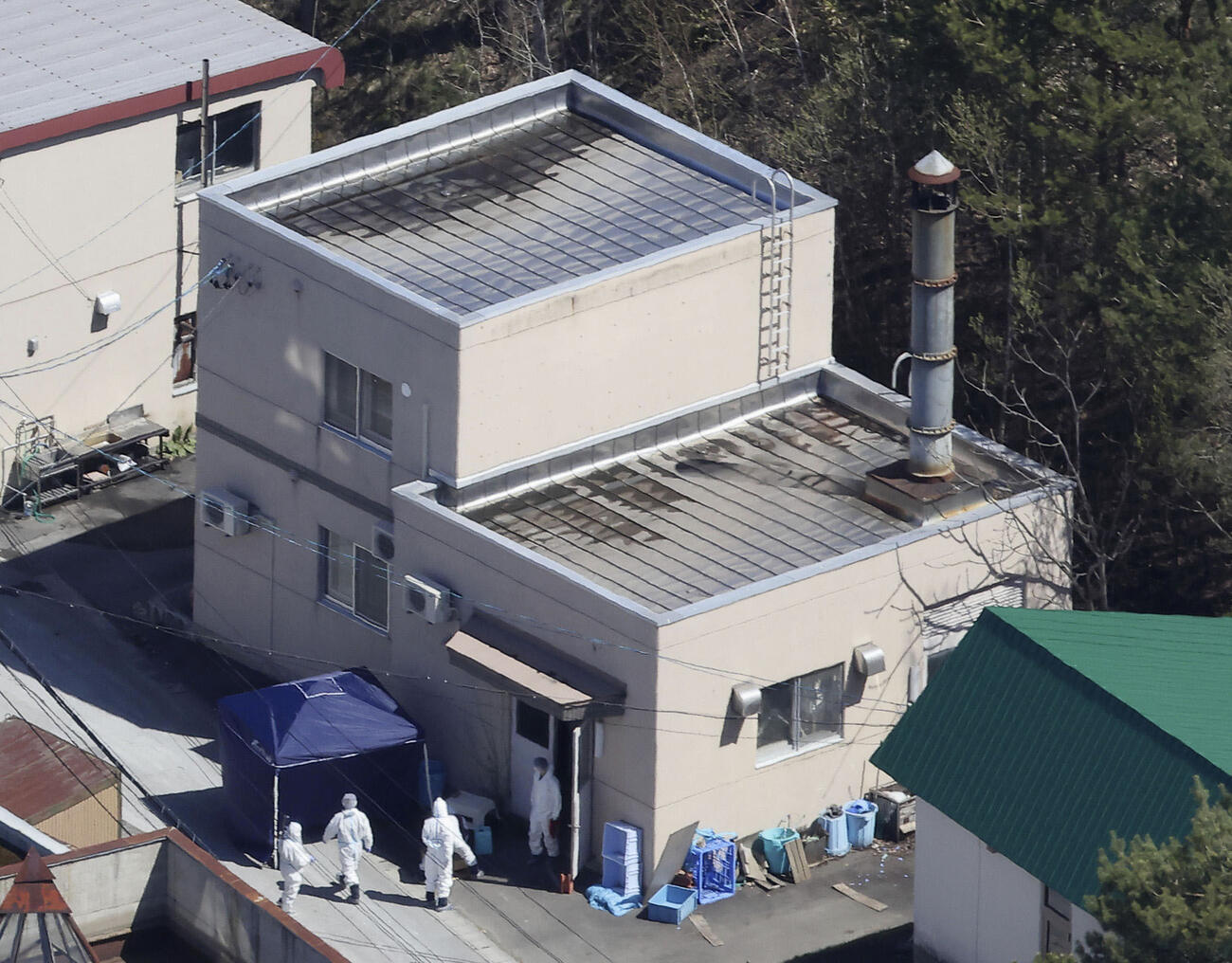 旭山動物園の現場検証で、焼却炉がある建物に入る捜査員ら＝4月25日(共同)