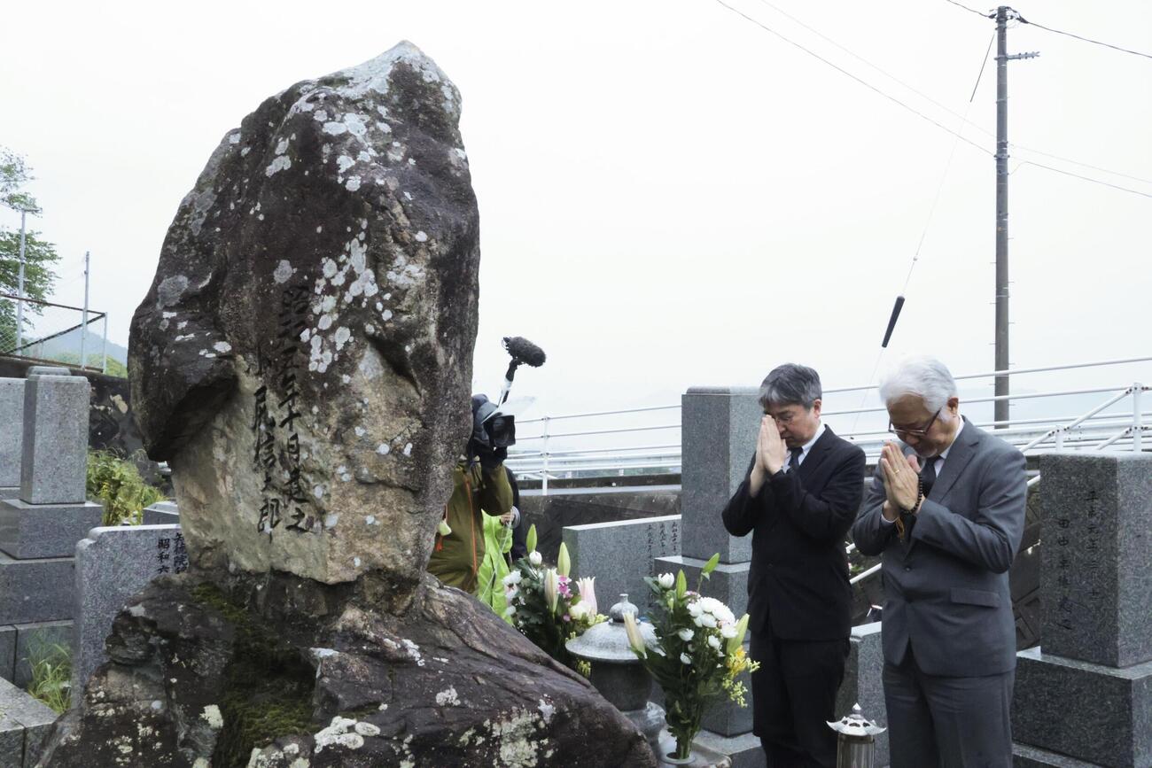 小尻知博記者の墓前で手を合わせる、朝日新聞社の龍沢正之大阪本社編集局長（左）ら＝3日午前、広島県呉市(共同)