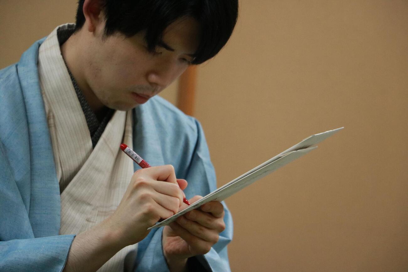 封じ手の封筒にサインする藤井聡太名人（日本将棋連盟提供）