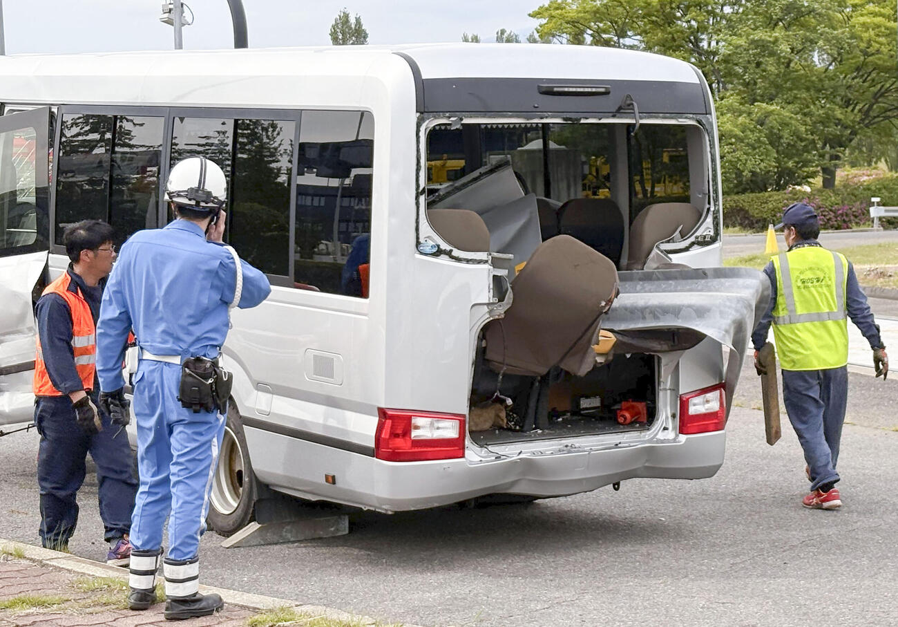 事故現場から移動されたマイクロバスを確認する警察官（共同）