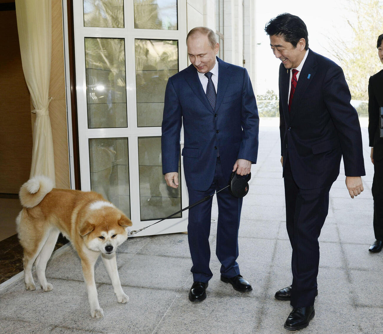2014年2月、秋田犬「ゆめ」を連れたロシアのプーチン大統領（左）に迎えられる安倍首相（当時）＝ソチ（共同）