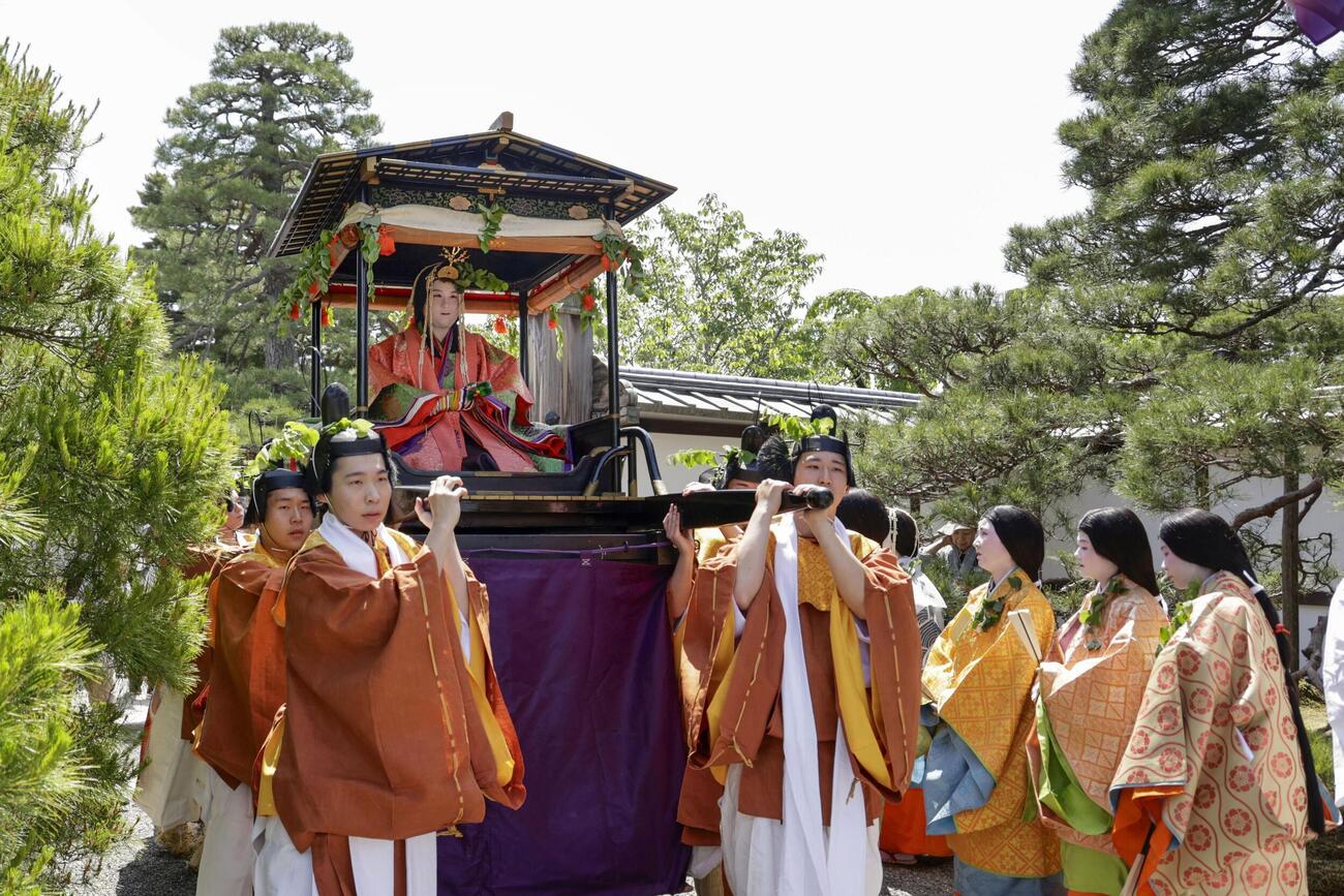 色鮮やかな平安装束姿で出発する、葵祭のヒロイン「斎王代」の塩見真桜さん＝15日午前、京都市