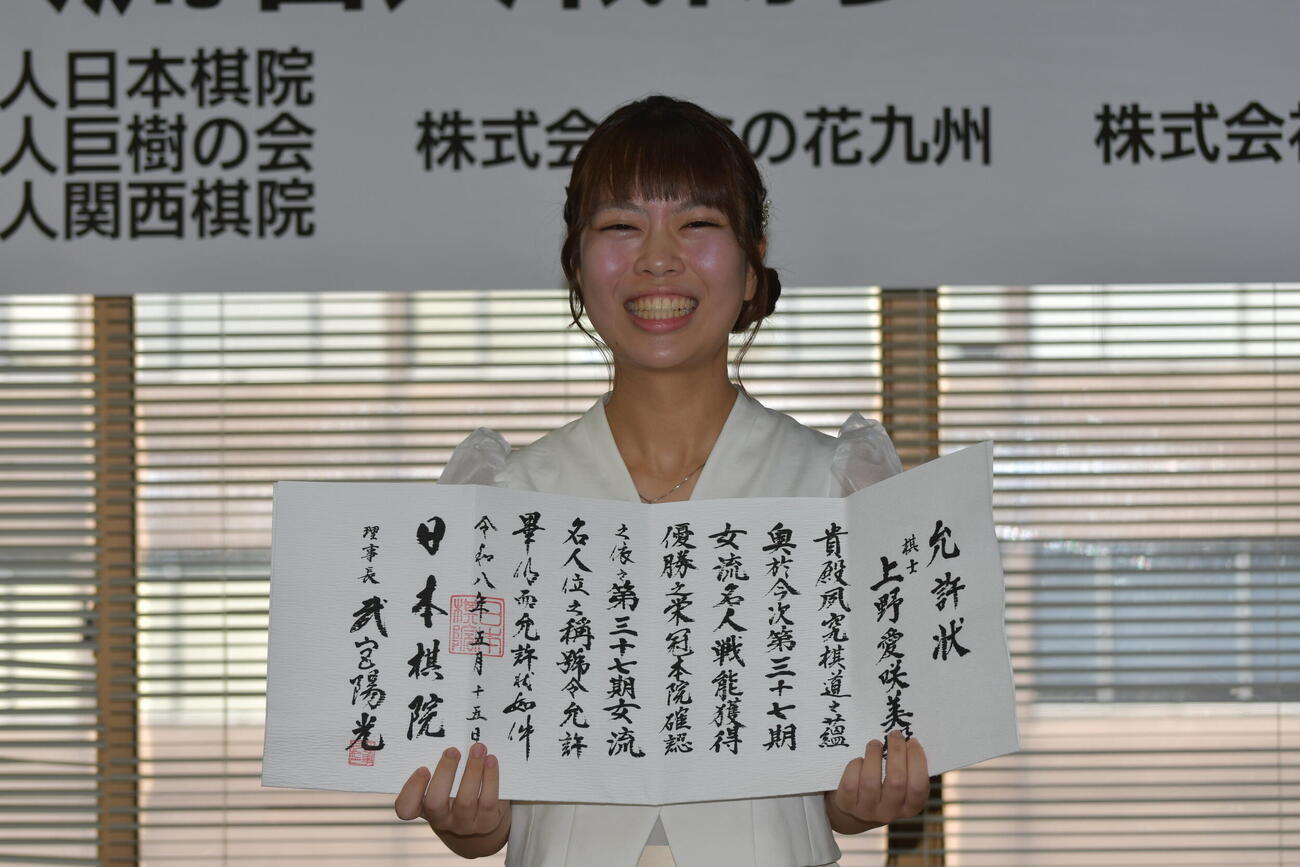 就位式で允許（いんきょ）状を手にする上野愛咲美女流名人